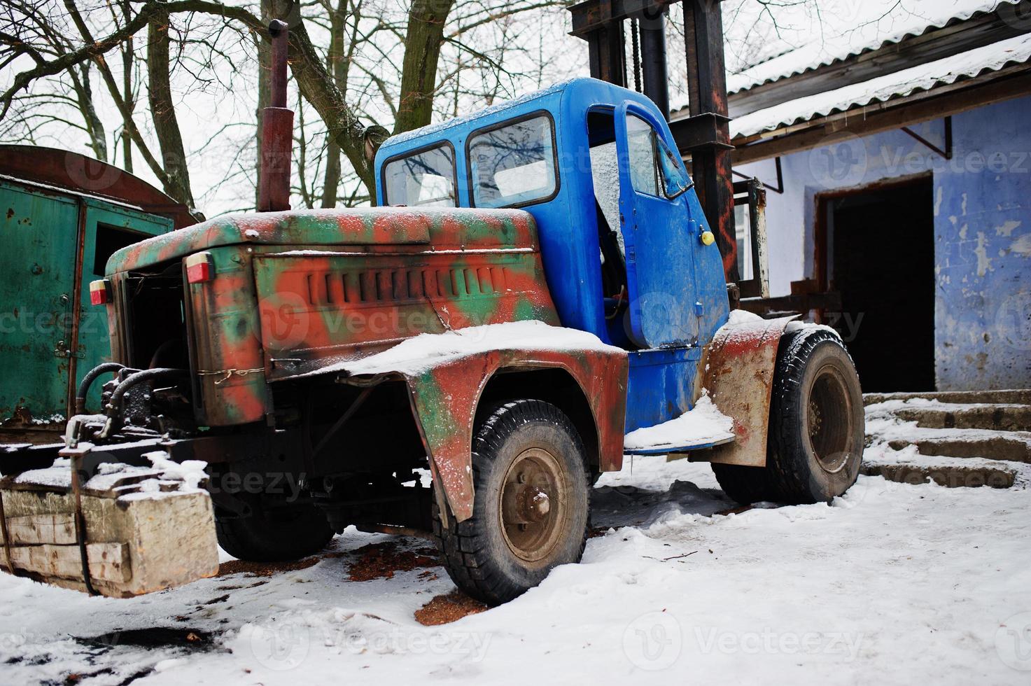 Rusty old soviet tractor covered by snow. photo