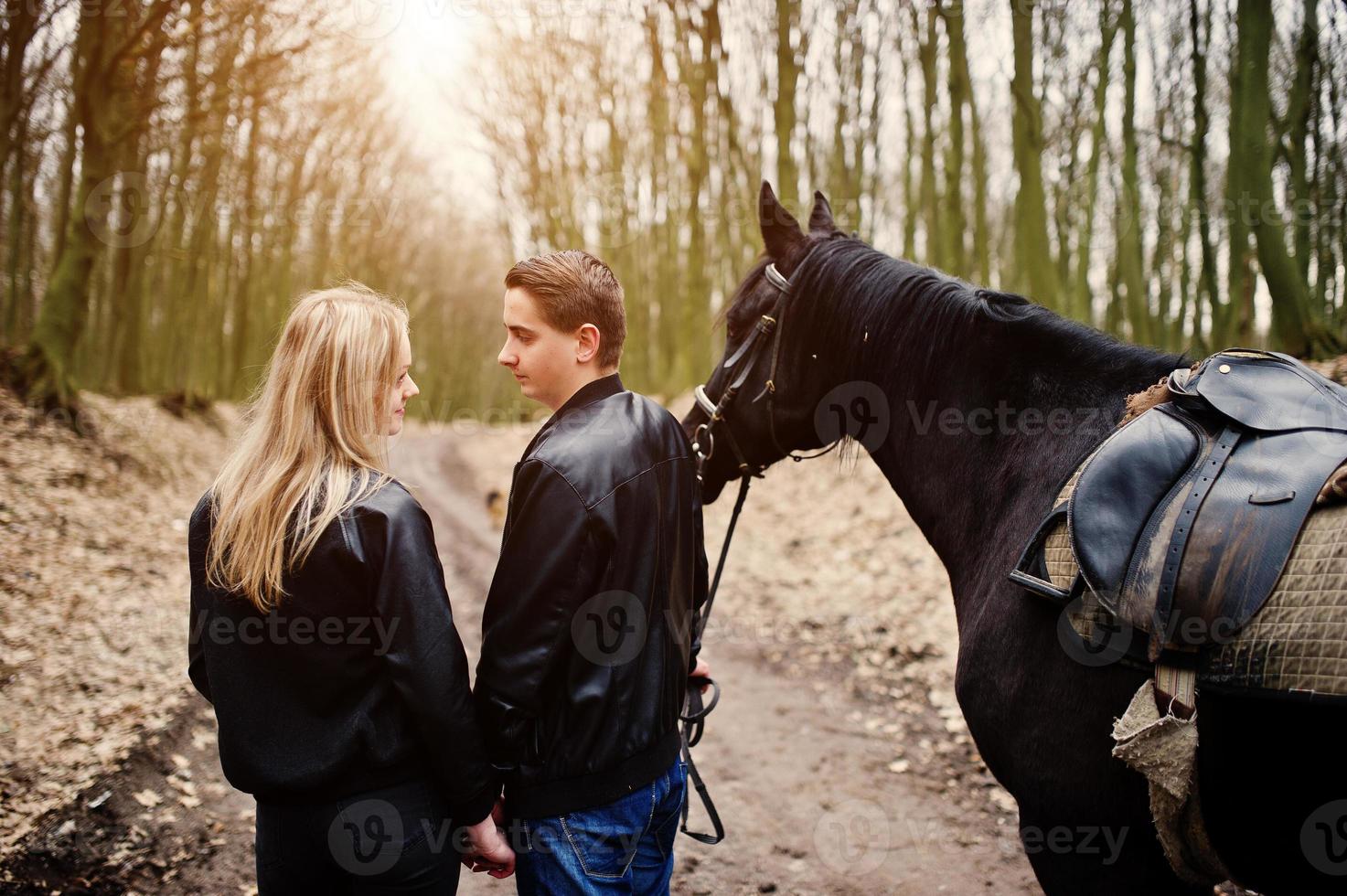 joven pareja elegante enamorada cerca de caballo en el bosque de otoño. foto