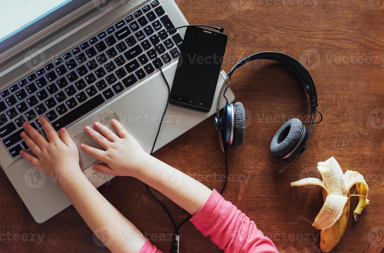 little girl presses the keyboard of his laptop photo