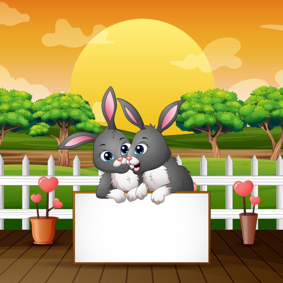 Cartoon bunnies holding blank sign in the park vector