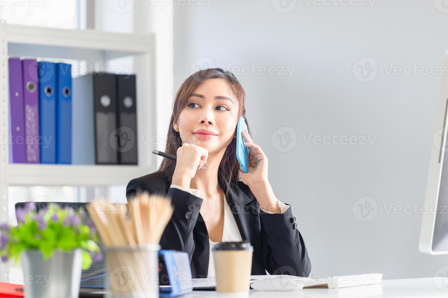 Smiling businesswoman using phone in office. Excited pretty girl using smartphone in office, woman working in her home office photo