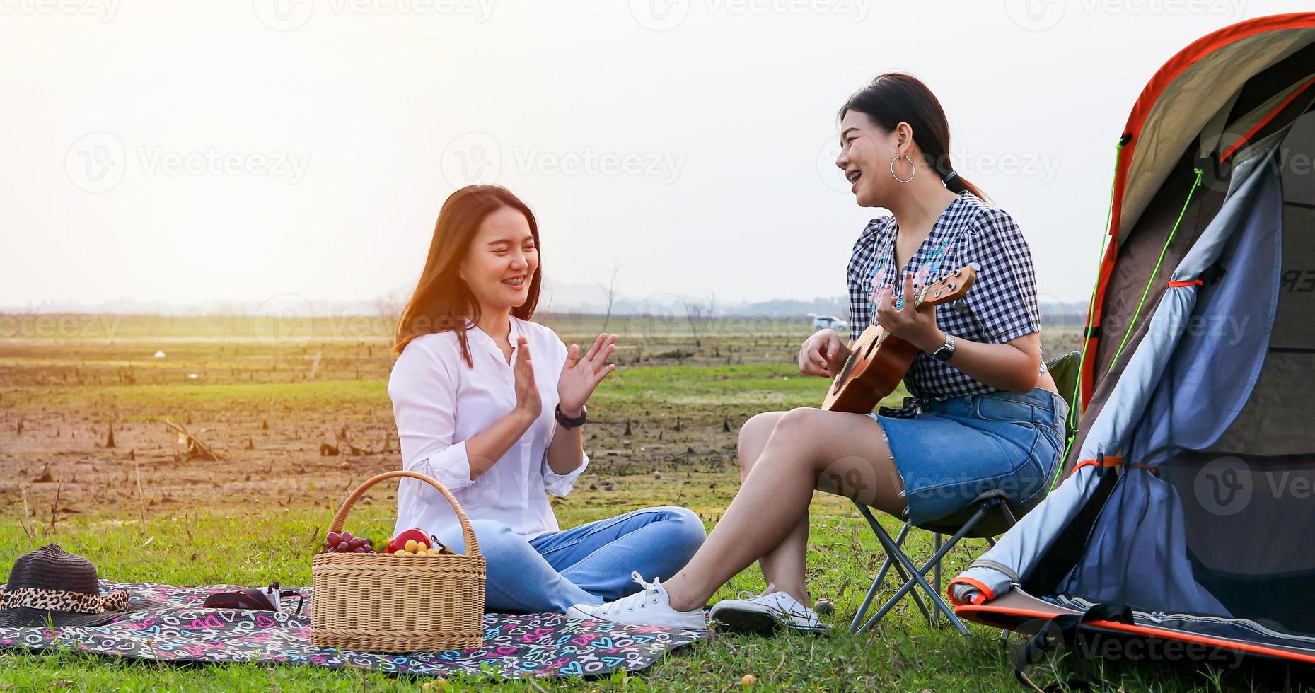 un grupo de amigos asiáticos tocando el ukelele y pasando el tiempo haciendo un picnic en las vacaciones de verano. son felices y se divierten en las vacaciones. foto
