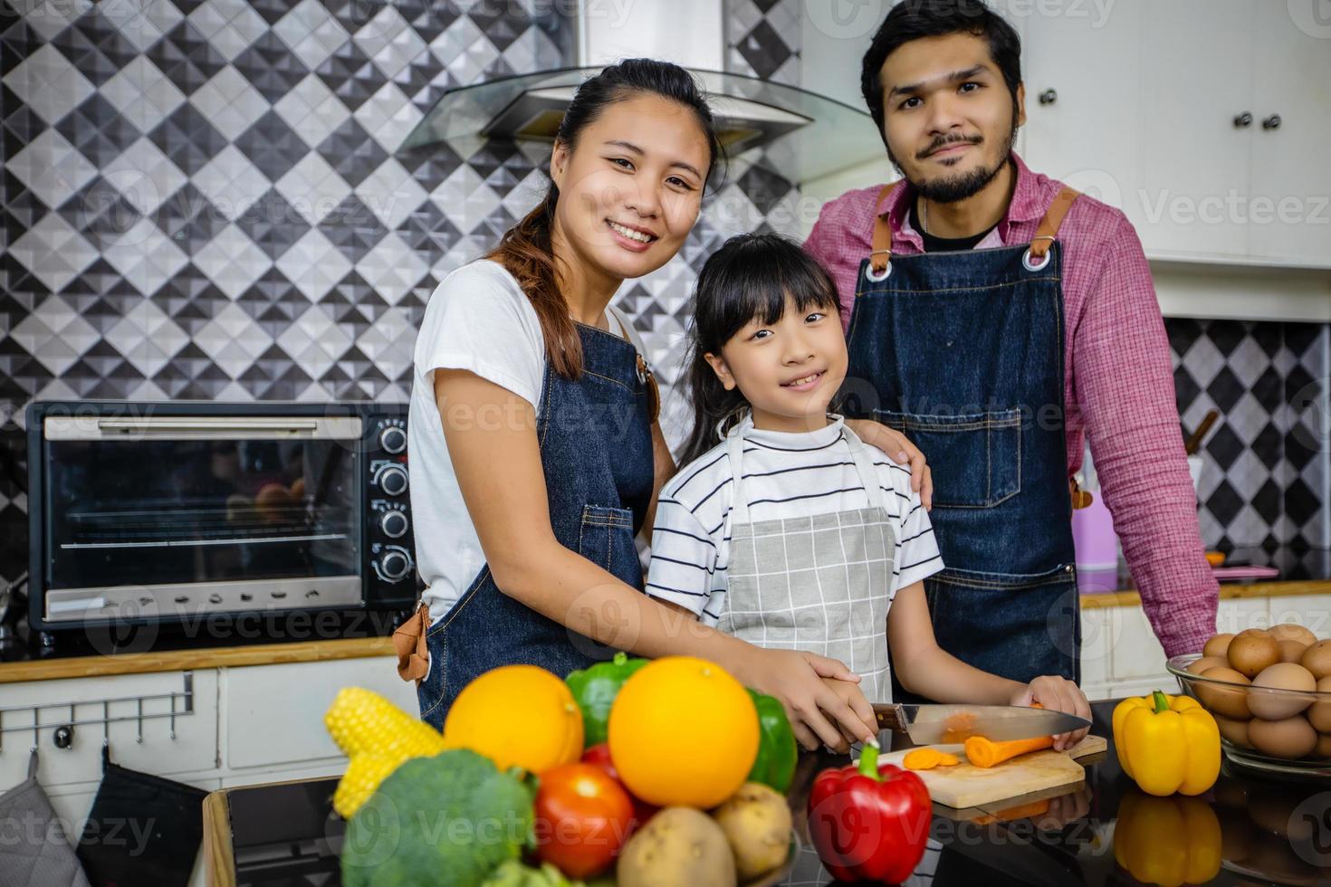 Happy Family have Dad, Mom and their little daughter Cooking Together in the Kitchen photo