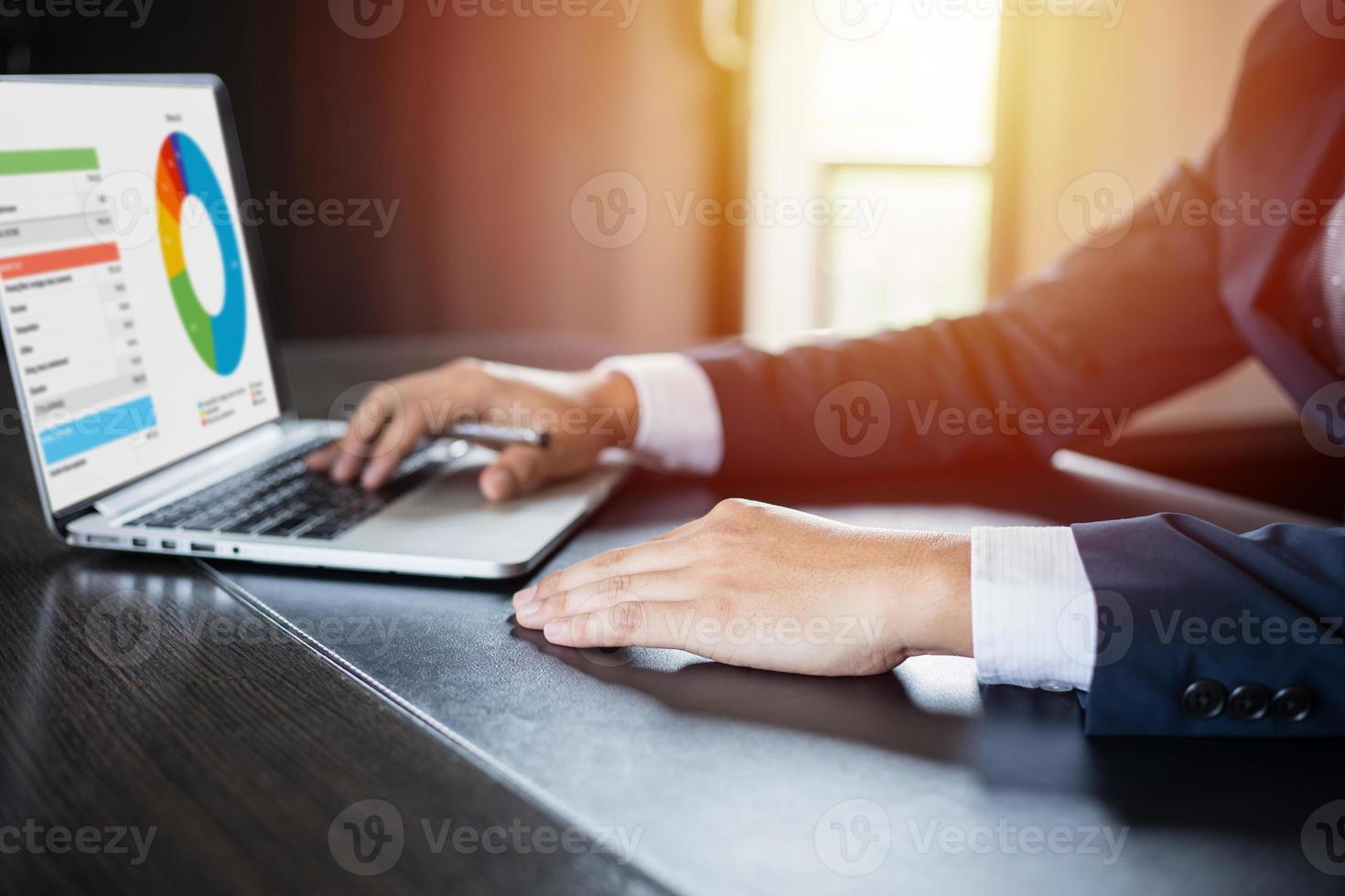 Asian businesswomen holding a pen and analysis documents on office table with laptop computer and graph financial diagram working in the background photo