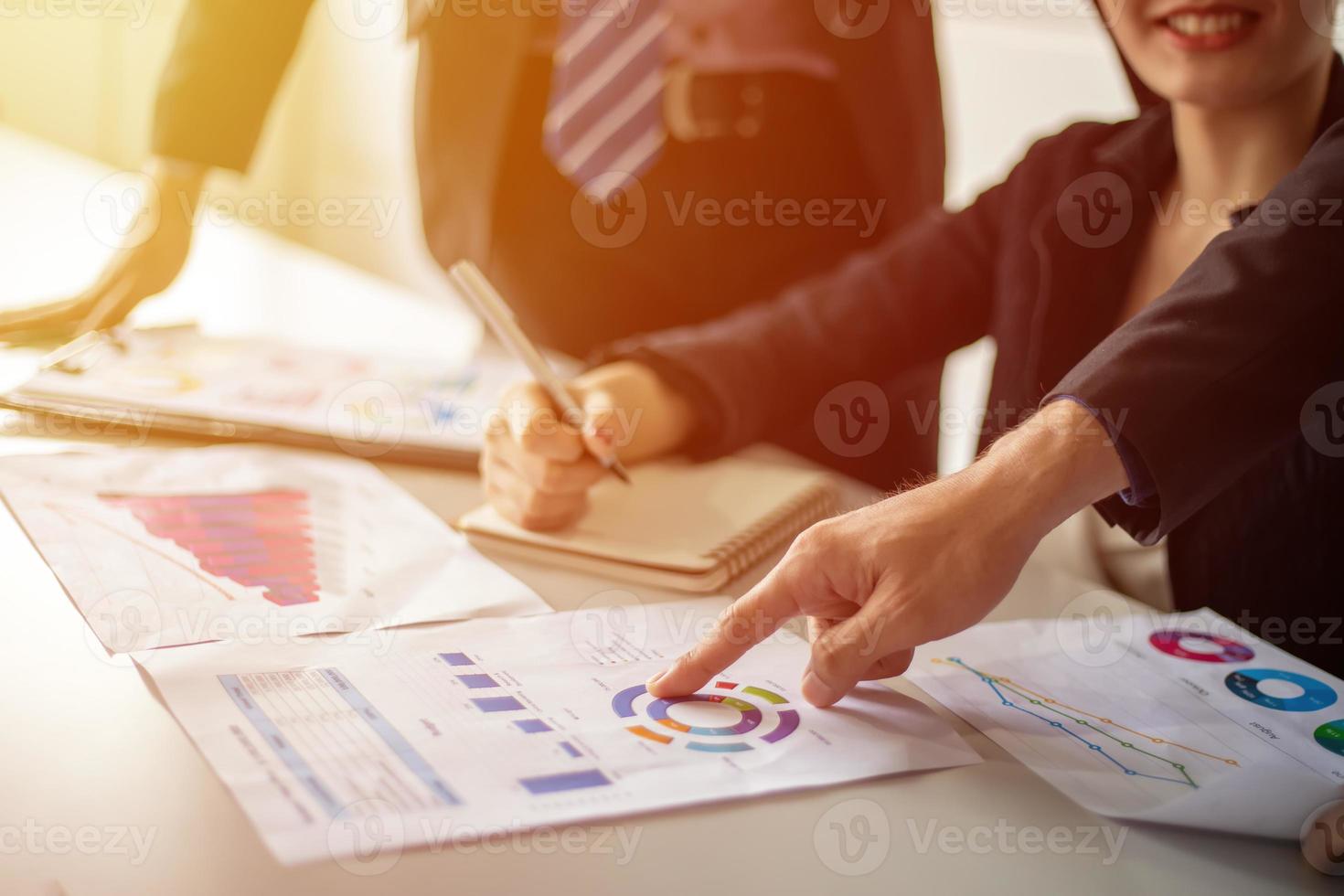 Asian businessmen and women working and point on graph financial diagram and analysis documents on office table photo