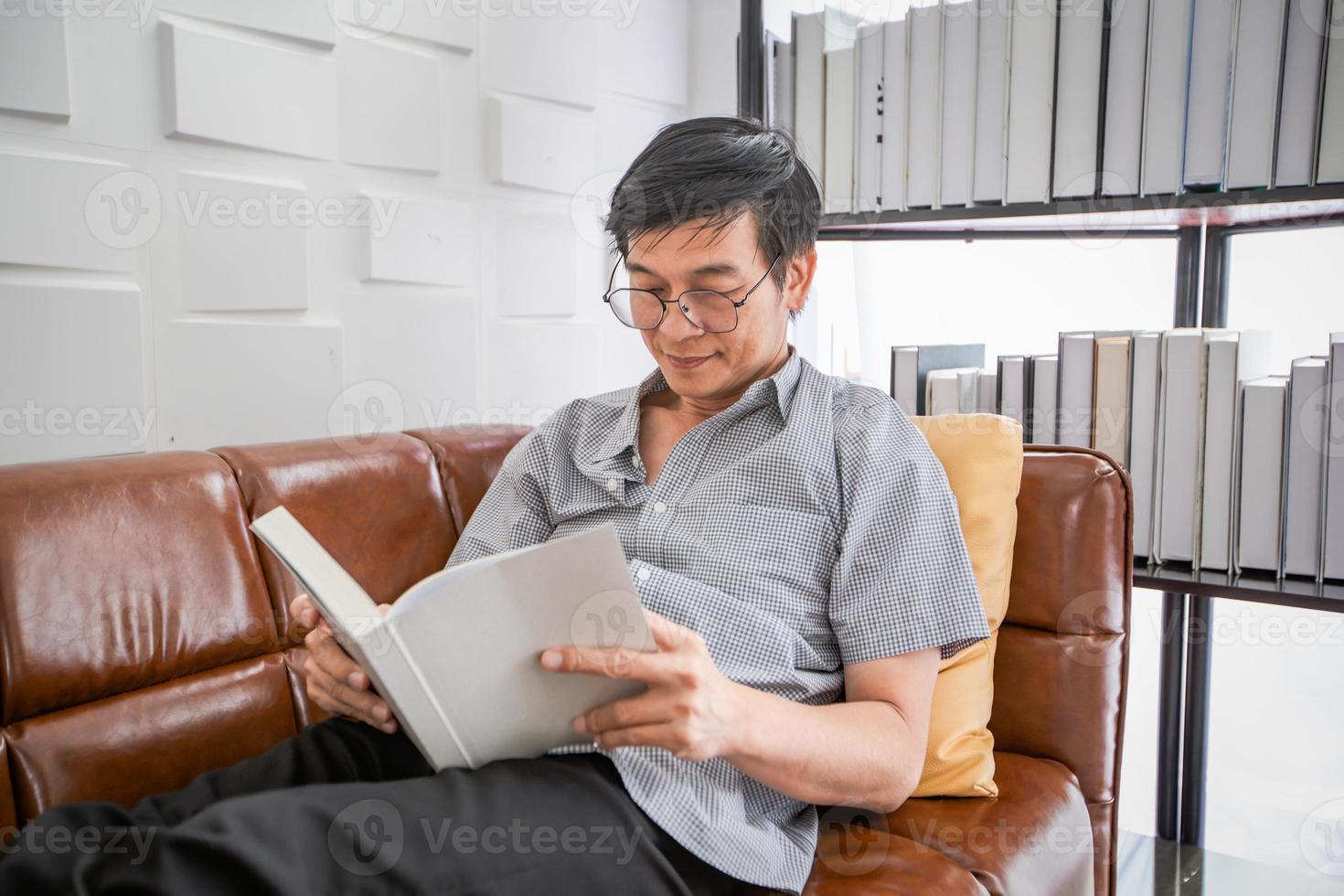Senior Asian man reading book on sofa in living room at home ,Portrait of Asian elderly man is Relaxing and Happiness With Read a Magazine  at home photo