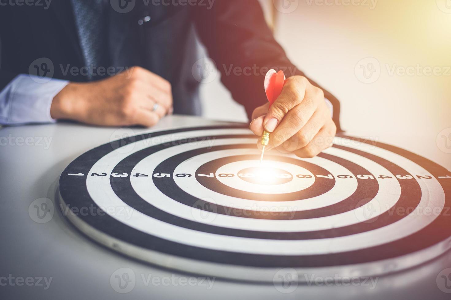 Business man holding dart hits Bullseye is a target and goal of business marketing as concept. photo