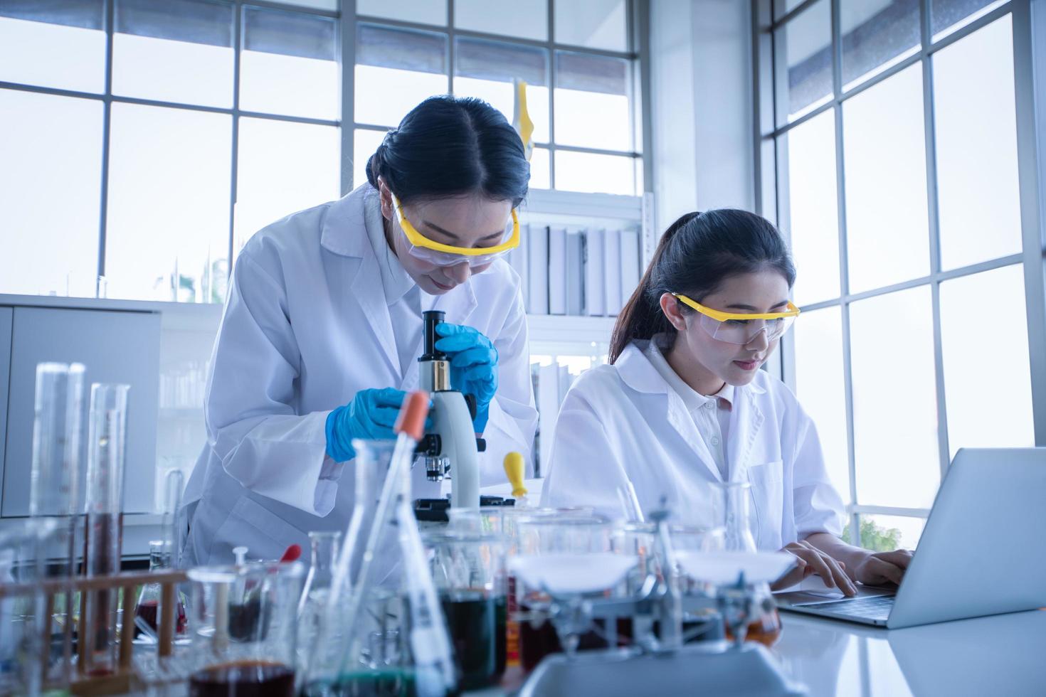 La investigación médica y los científicos están trabajando con un microscopio y una tableta y tubos de ensayo, micropipetas y resultados de análisis en un laboratorio. foto