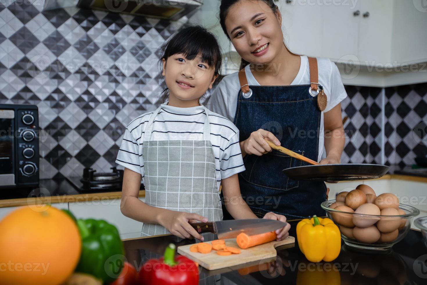 las familias asiáticas están cocinando y los padres están enseñando a sus hijas a cocinar en la cocina de casa. actividades familiares en vacaciones y felices en concepto de recreación foto