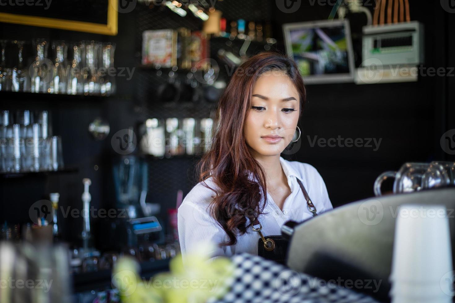 Las mujeres asiáticas barista sonriendo y usando la máquina de café en el mostrador de la cafetería - mujer trabajadora propietario de una pequeña empresa comida y bebida concepto de cafetería foto