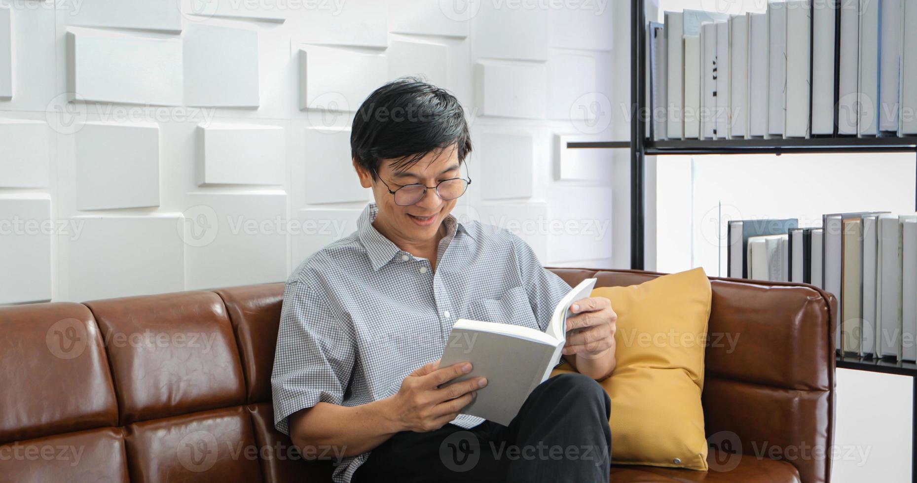 Senior Asian man reading book on sofa in living room at home ,Portrait of Asian elderly man is Relaxing and Happiness With Read a Magazine photo