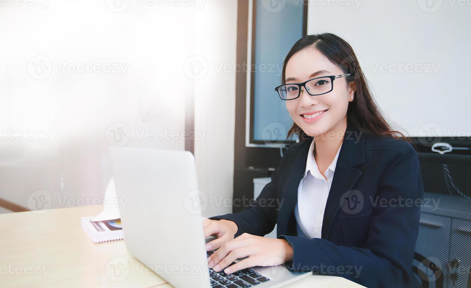 Mujeres de negocios asiáticas que usan el cuaderno y sonríen felices por trabajar foto