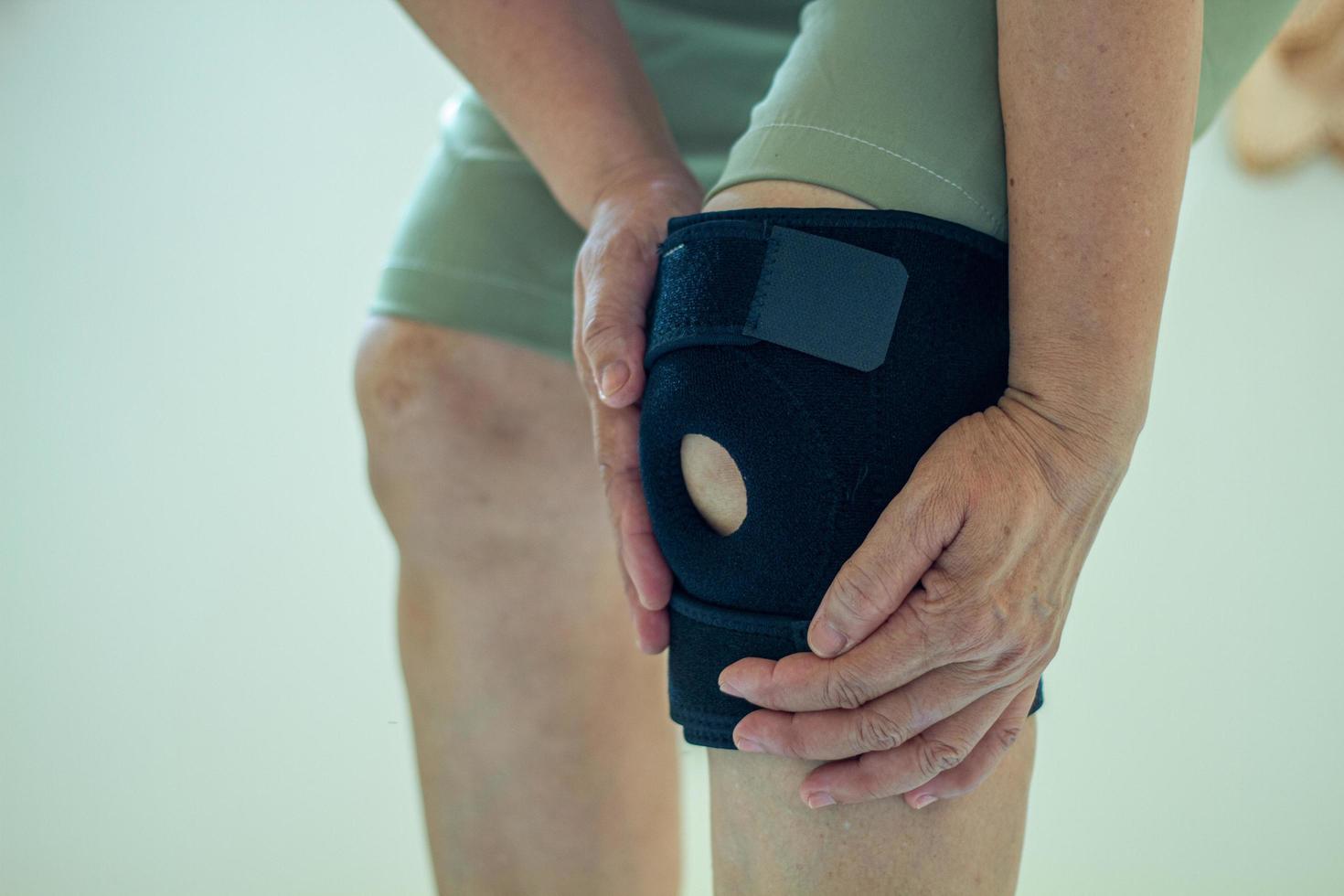 old Asian women to knee injury and use knee support brace on leg photo