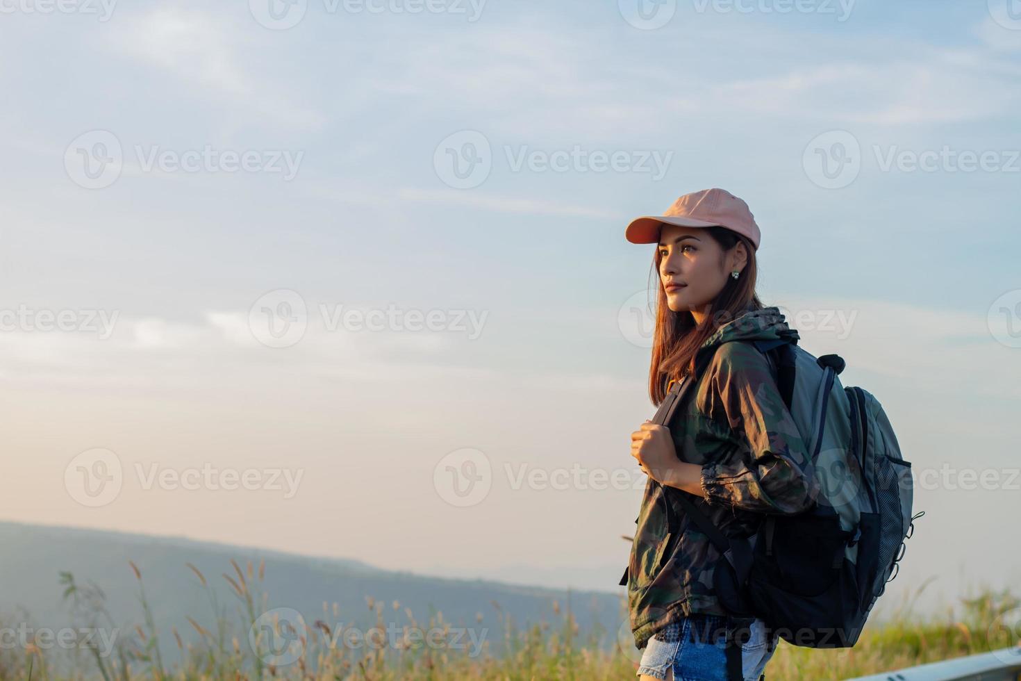 Portrait Asian woman backpacking. She was smiling and happy to travel at sunrise seaside mountain peak photo