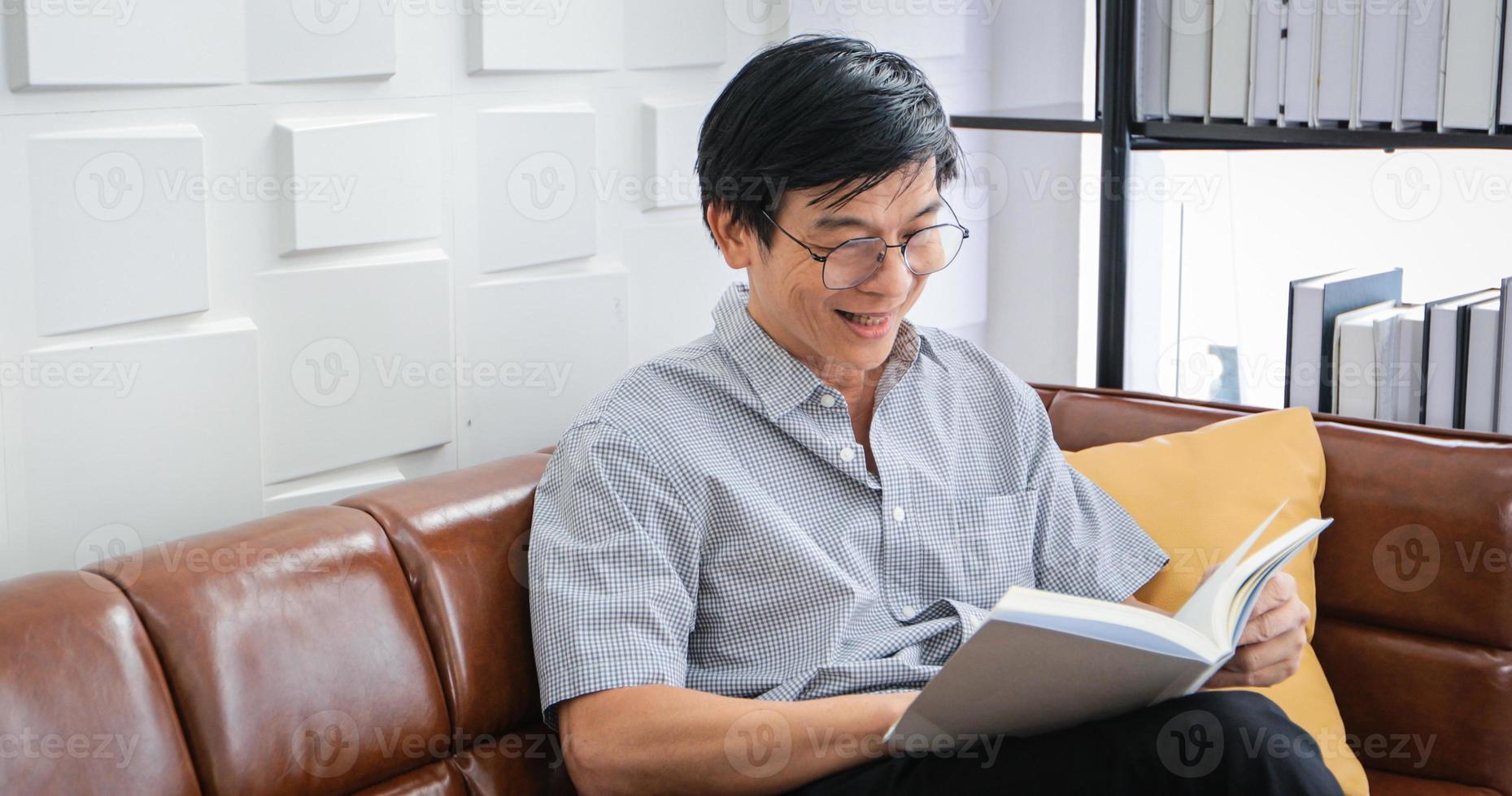 Senior Asian man reading book on sofa in living room at home ,Portrait of Asian elderly man is Relaxing and Happiness With Read a Magazine  at home photo