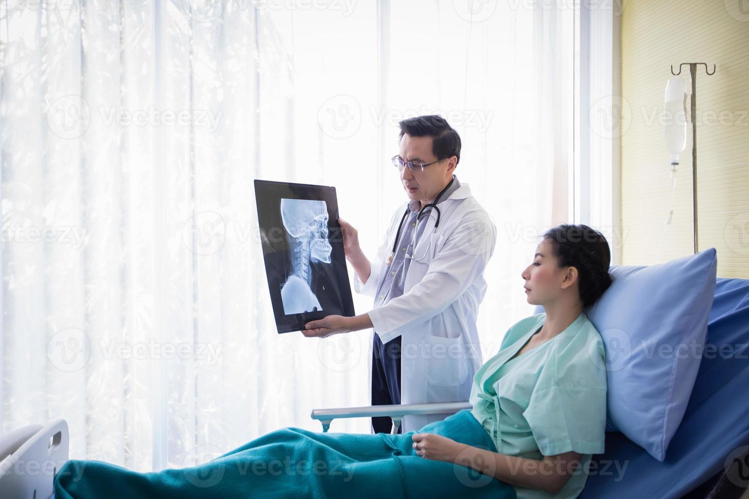 The doctor is explaining about the brain X-ray results to a female patient lying in bed at a hospital photo