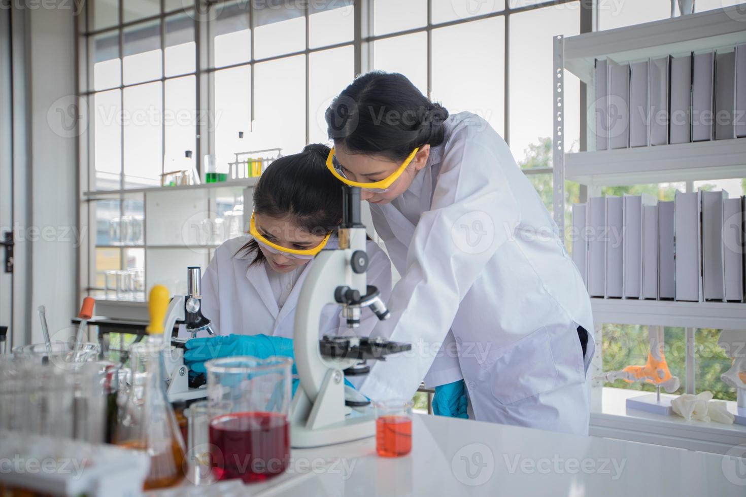 La investigación médica y los científicos están trabajando con un microscopio y una tableta y tubos de ensayo, micropipetas y resultados de análisis en un laboratorio. foto