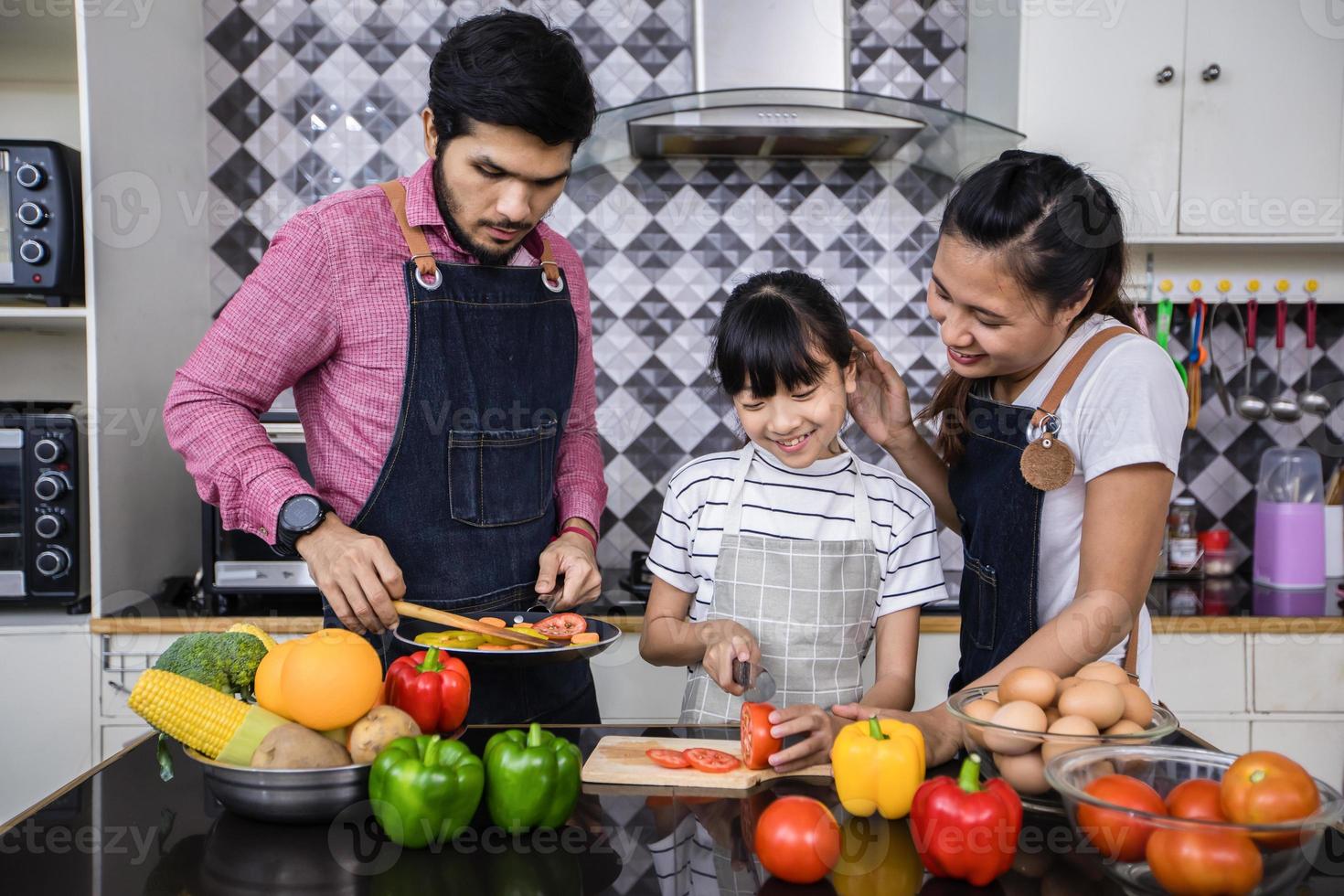 las familias asiáticas están cocinando y los padres están enseñando a sus hijas a cocinar en la cocina de casa. actividades familiares en vacaciones y felices en concepto de recreación foto