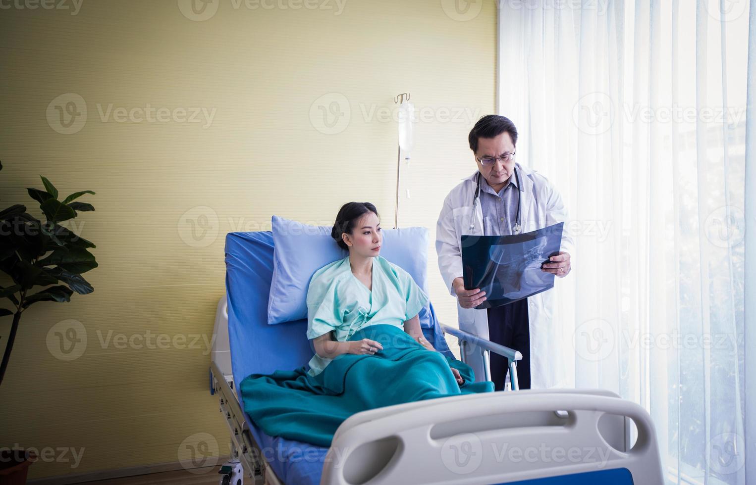 el médico está explicando los resultados de la radiografía del cerebro a una paciente acostada en la cama de un hospital foto