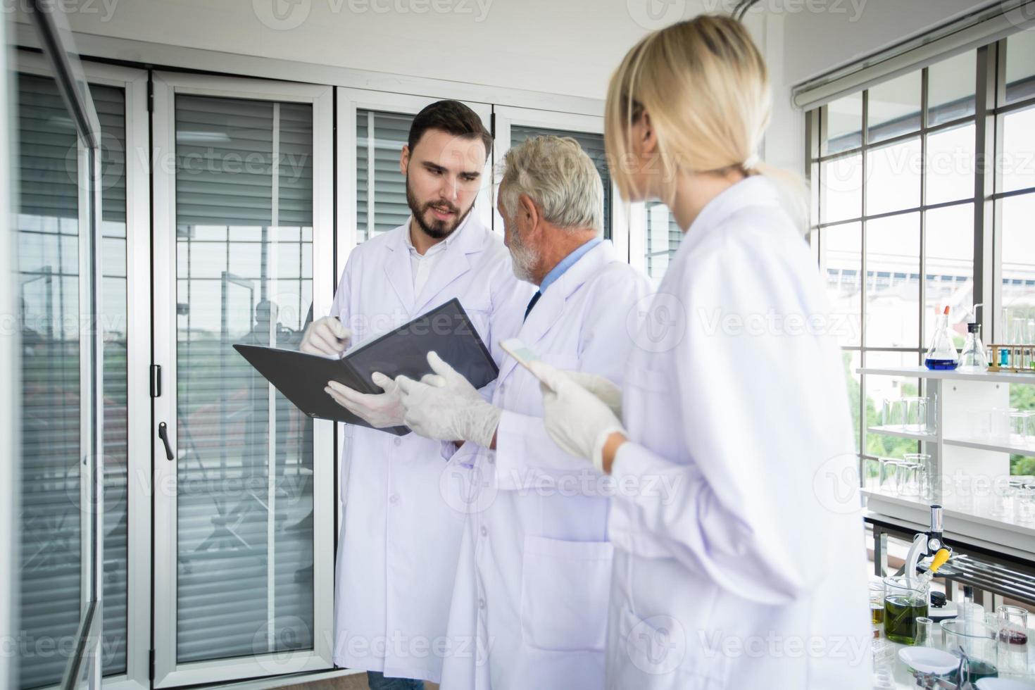 La investigación médica y los científicos están trabajando con un microscopio y una tableta y tubos de ensayo, micropipetas y resultados de análisis en un laboratorio. foto