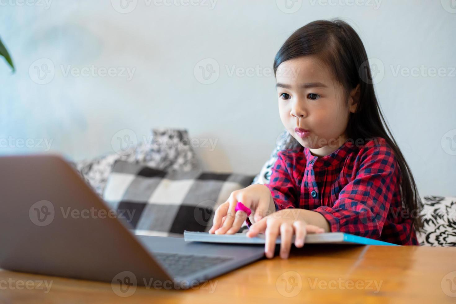 Asian girl or daughters use notebooks and technology for online learning during school holidays and watching cartoons at home. Educational concepts and activities of the family photo