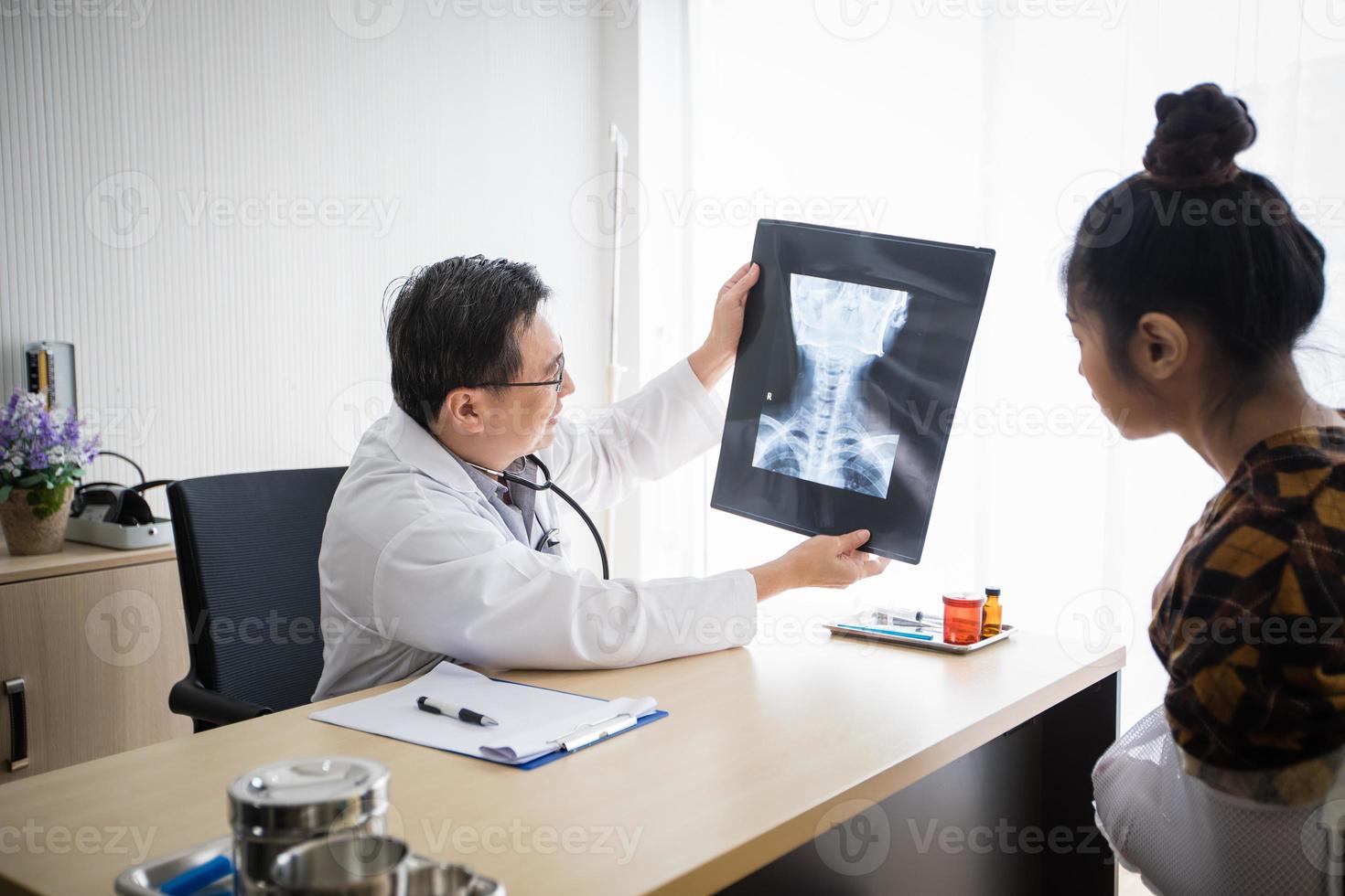 The doctor is explaining about the brain X-ray results to a female patient in his office at Hospitals photo