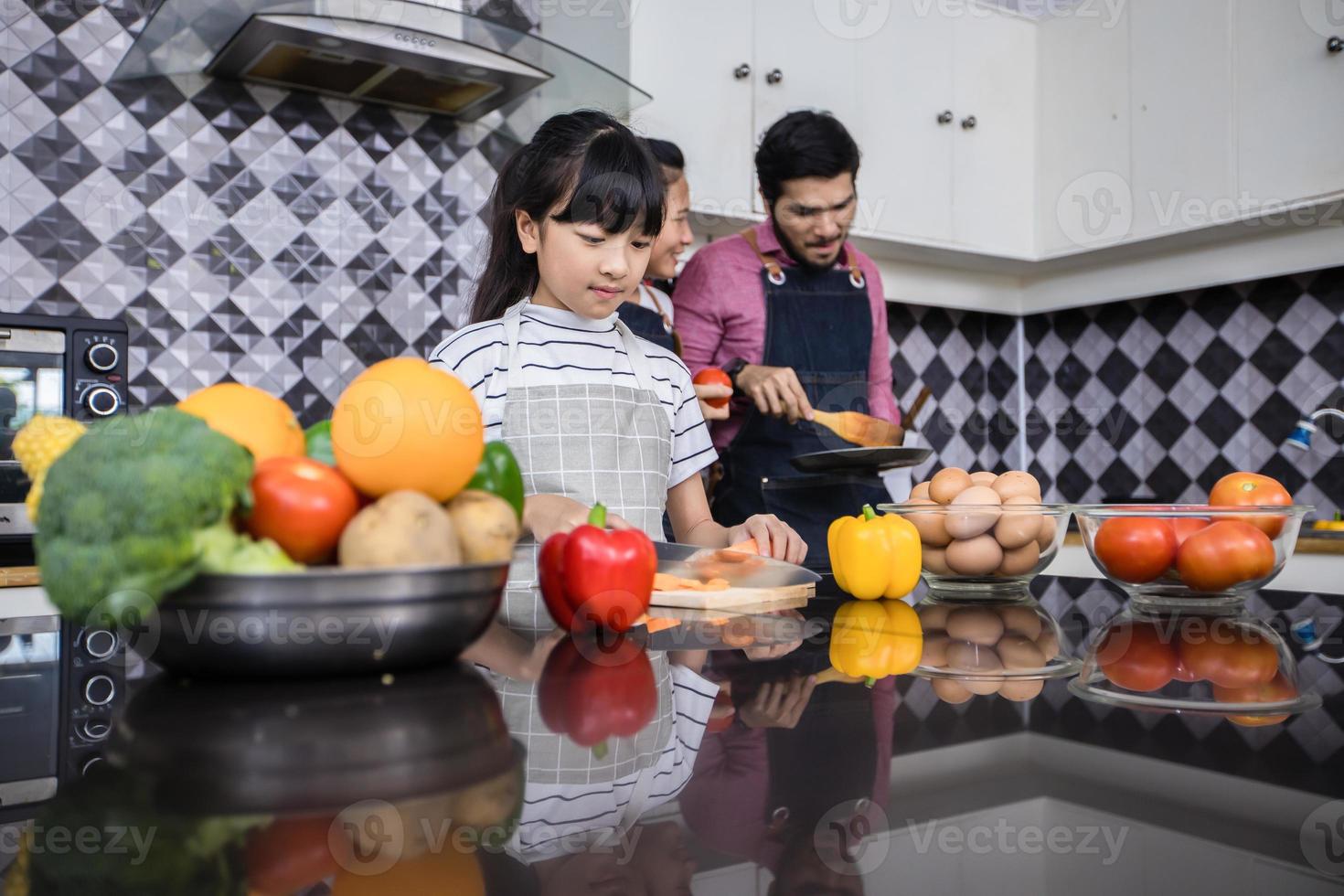 las familias asiáticas están cocinando y los padres están enseñando a sus hijas a cocinar en la cocina de casa. actividades familiares en vacaciones y felices en concepto de recreación foto