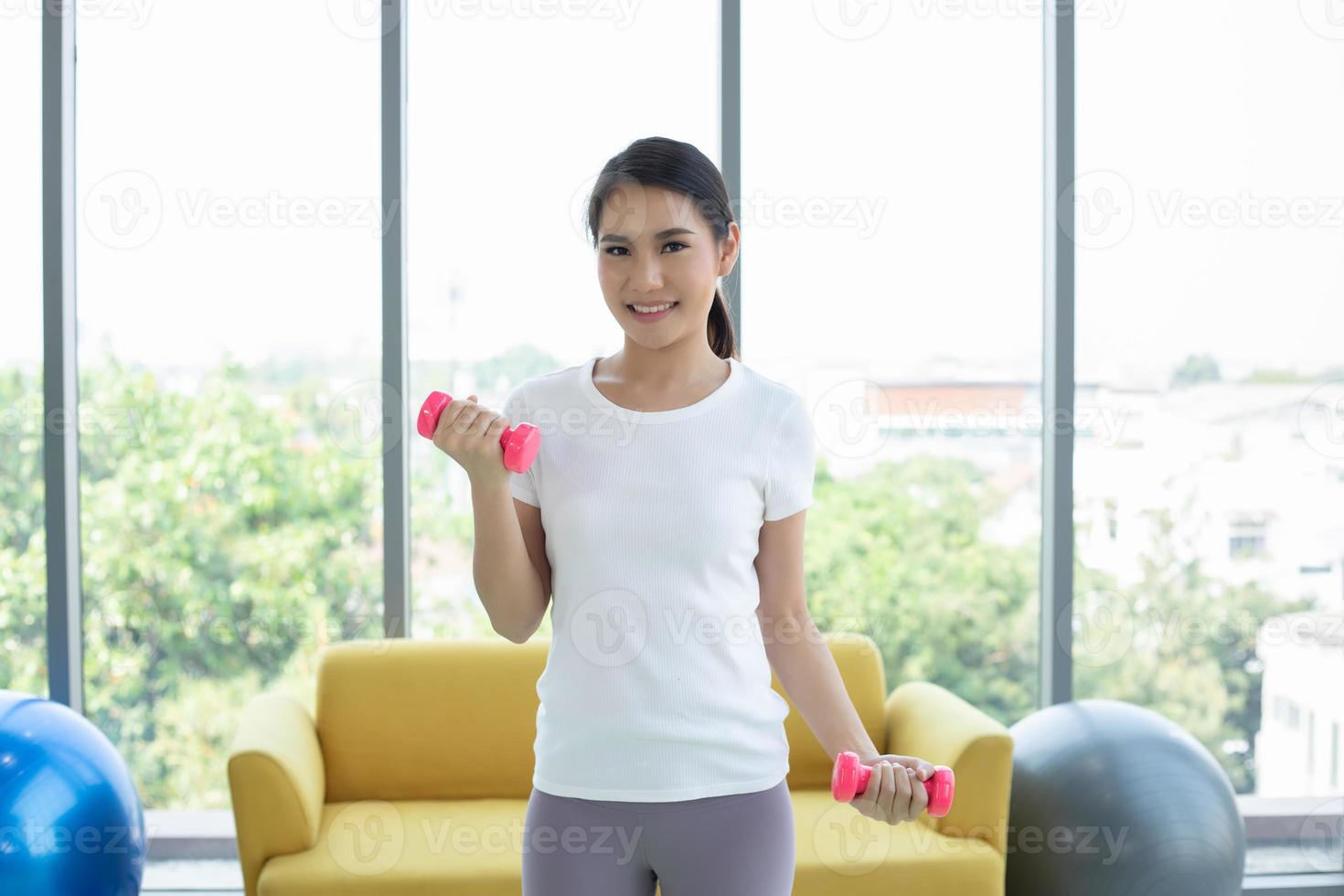 mujer asiática haciendo ejercicio con pesas en casa foto