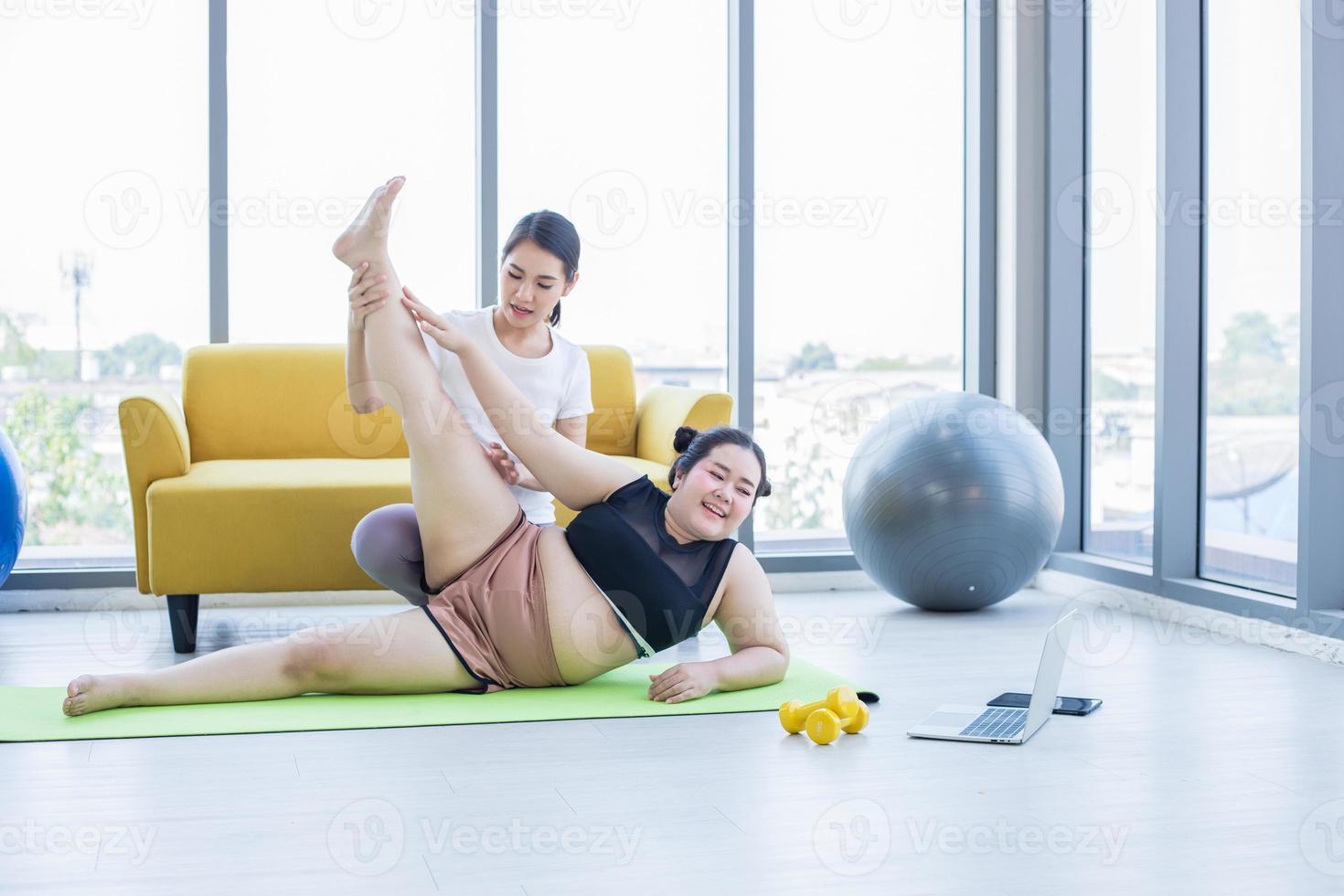 dos mujeres asiáticas viendo y aprendiendo yoga haciendo ejercicio en línea en un ordenador portátil en casa, actividad conceptual y relajación en casa foto