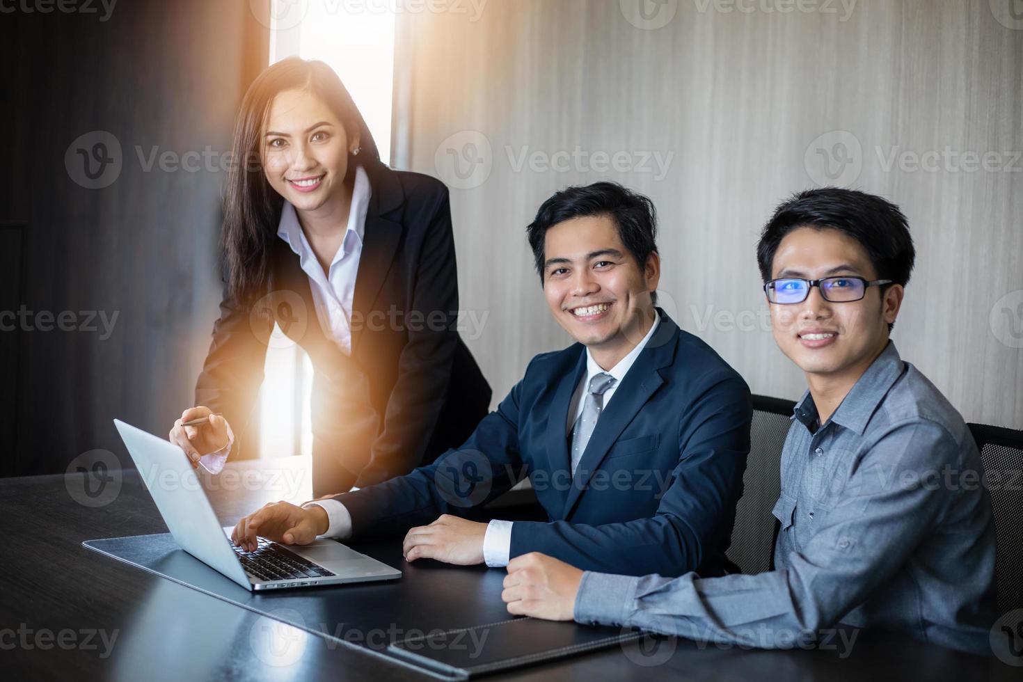 Hombres de negocios asiáticos y grupo que usan el cuaderno para socios comerciales que discuten documentos e ideas en reuniones y mujeres de negocios sonriendo felices por trabajar foto
