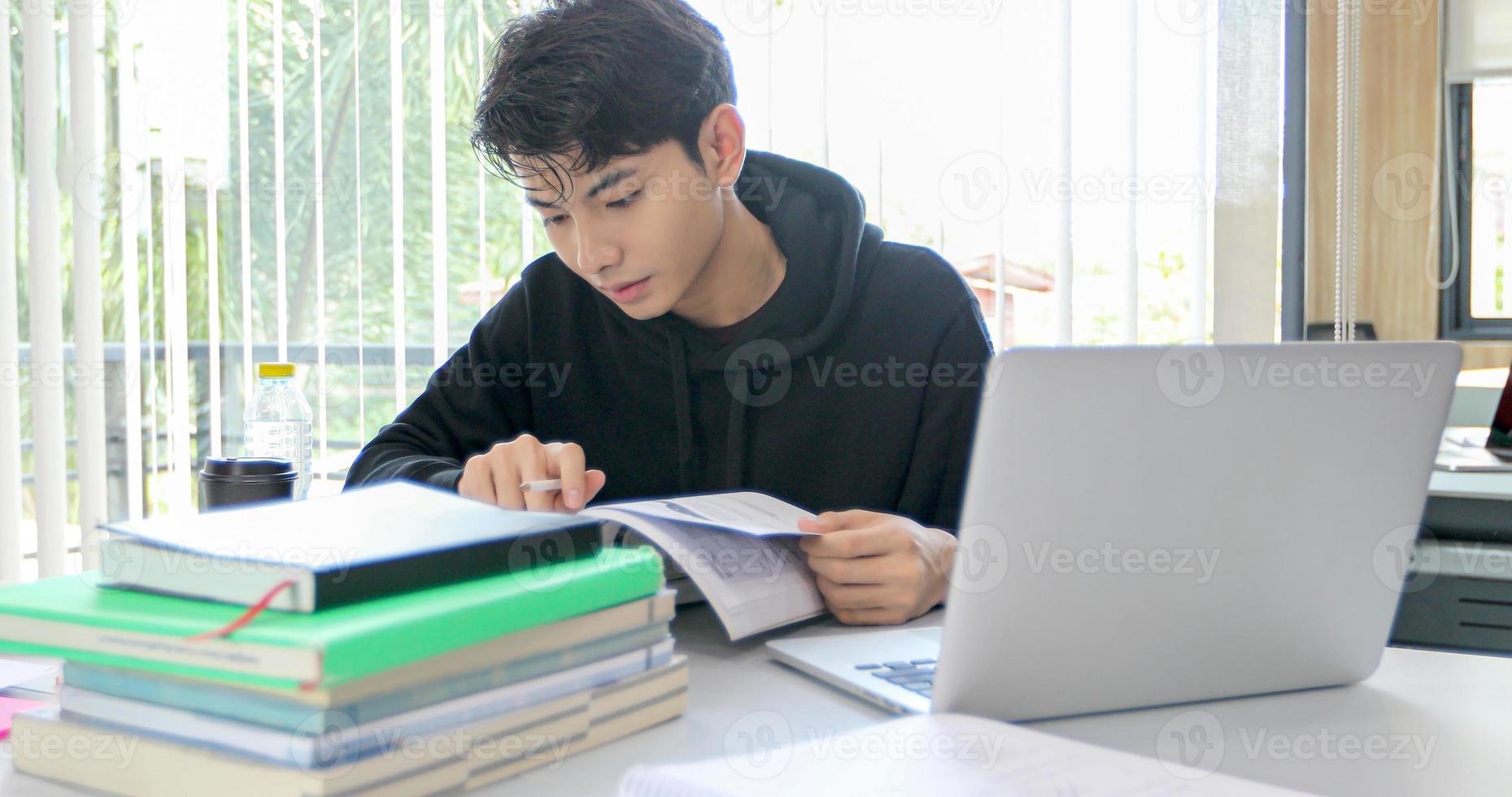 los estudiantes asiáticos sonríen y leen libros y usan un cuaderno para ayudar a compartir ideas en el trabajo y el proyecto. y también repasar el libro antes del examen foto