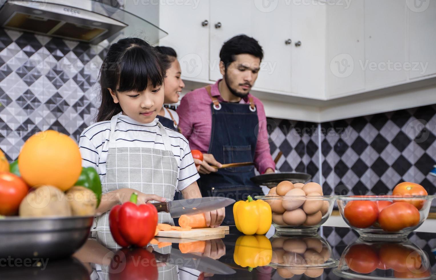 las familias asiáticas están cocinando y los padres están enseñando a sus hijas a cocinar en la cocina de casa. actividades familiares en vacaciones y felices en concepto de recreación foto