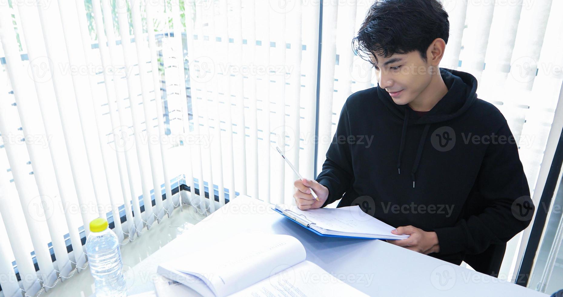 Asian men Students Smile and reading book and using notebook for helps to share ideas in the work and project. And also review the book before the exam photo