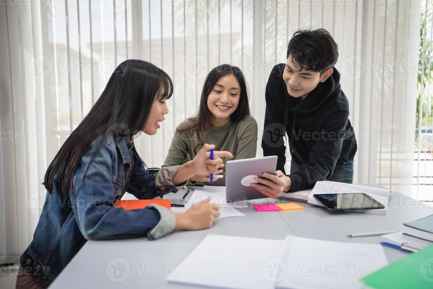 Group Asian  Students Smile and reading book and using notebook for helps to share ideas in the work and project. And also review the book before the exam photo
