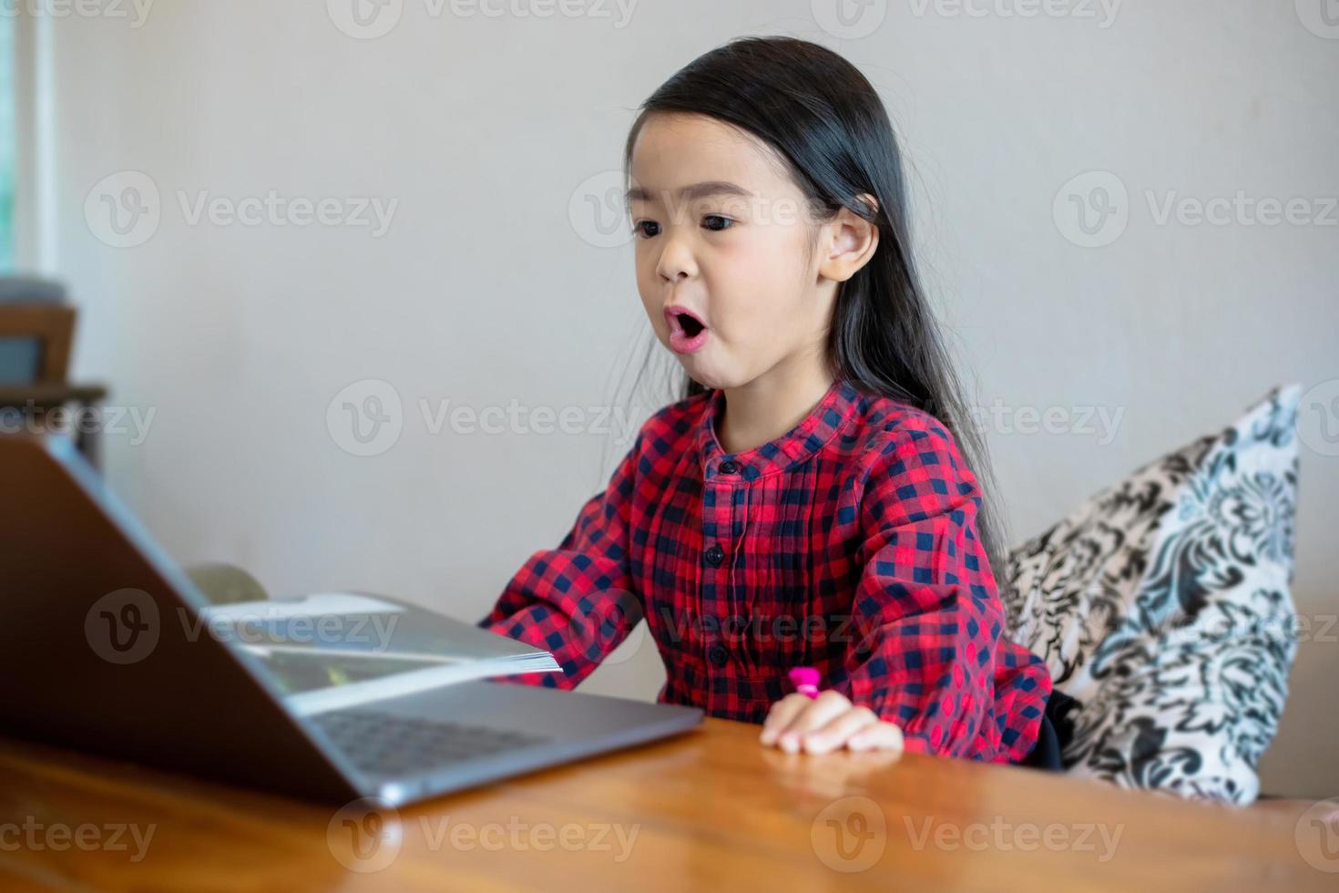 Asian girl or daughters use notebooks and technology for online learning during school holidays and watching cartoons at home. Educational concepts and activities of the family photo