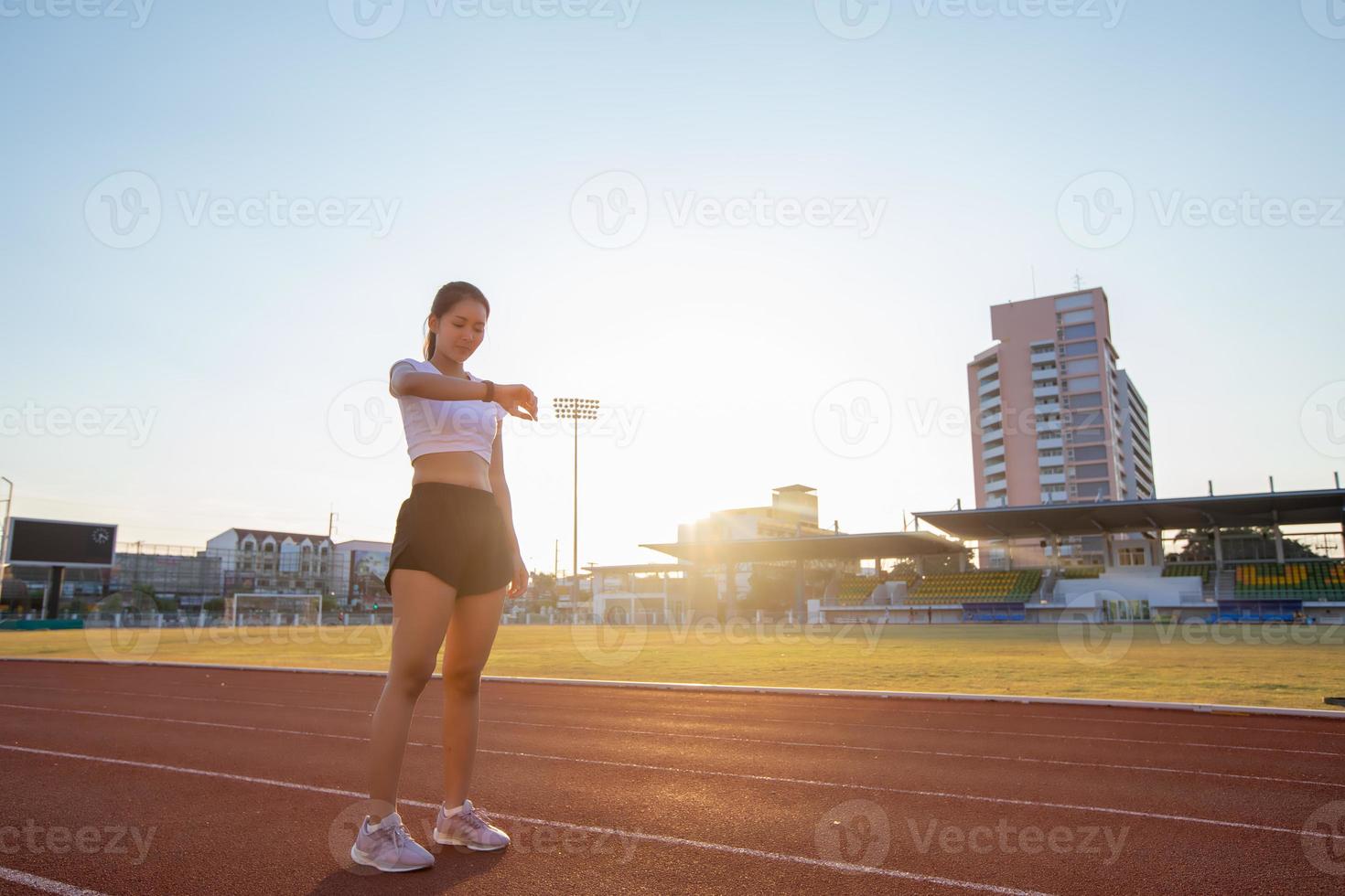 Asian women is watching the sport watch or smart watch for jogging on stadium track -healthy lifestyle and sport concepts photo