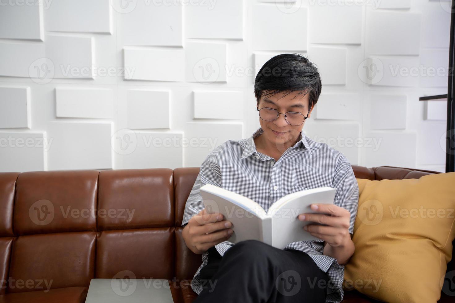 Senior Asian man reading book on sofa in living room at home ,Portrait of Asian elderly man is Relaxing and Happiness With Read a Magazine photo