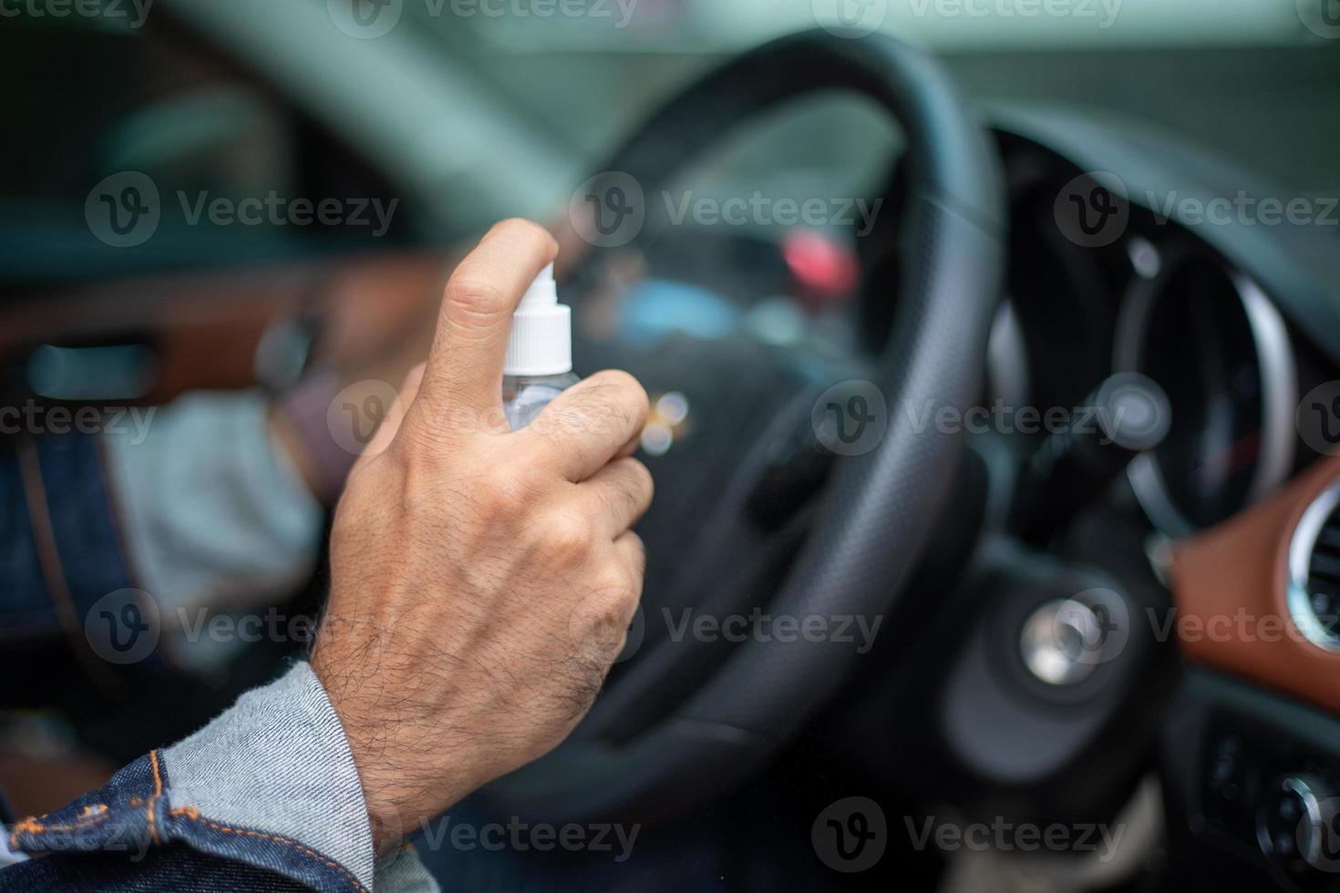 hombre asiático usando alcohol en aerosol para limpiar el auto para protegerse del coronavirus foto