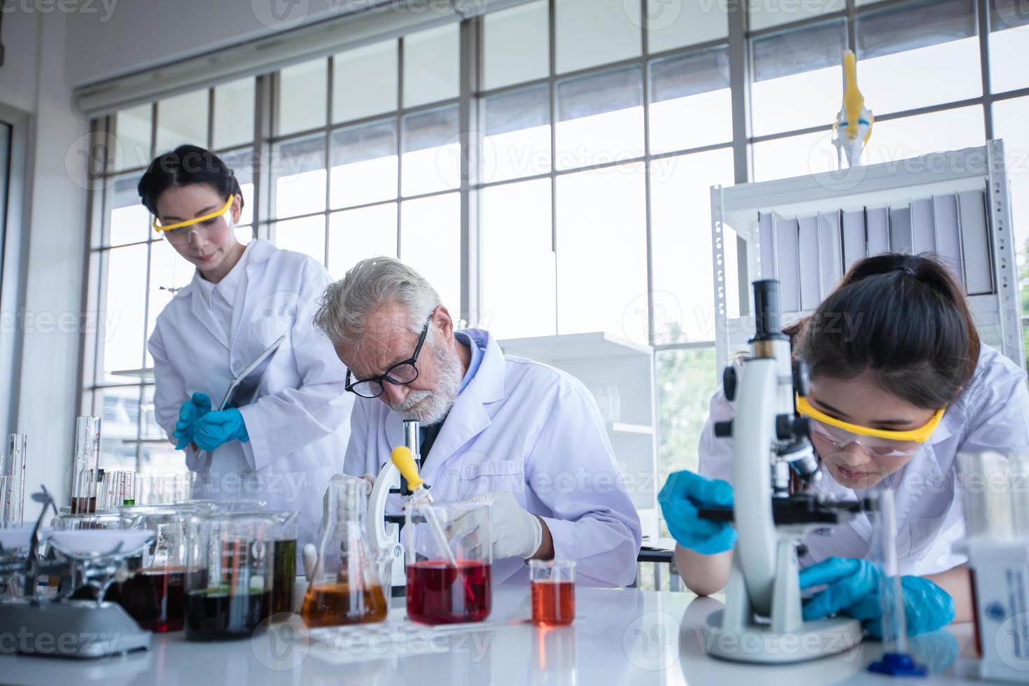 La investigación médica y los científicos están trabajando con un microscopio y una tableta y tubos de ensayo, micropipetas y resultados de análisis en un laboratorio. foto