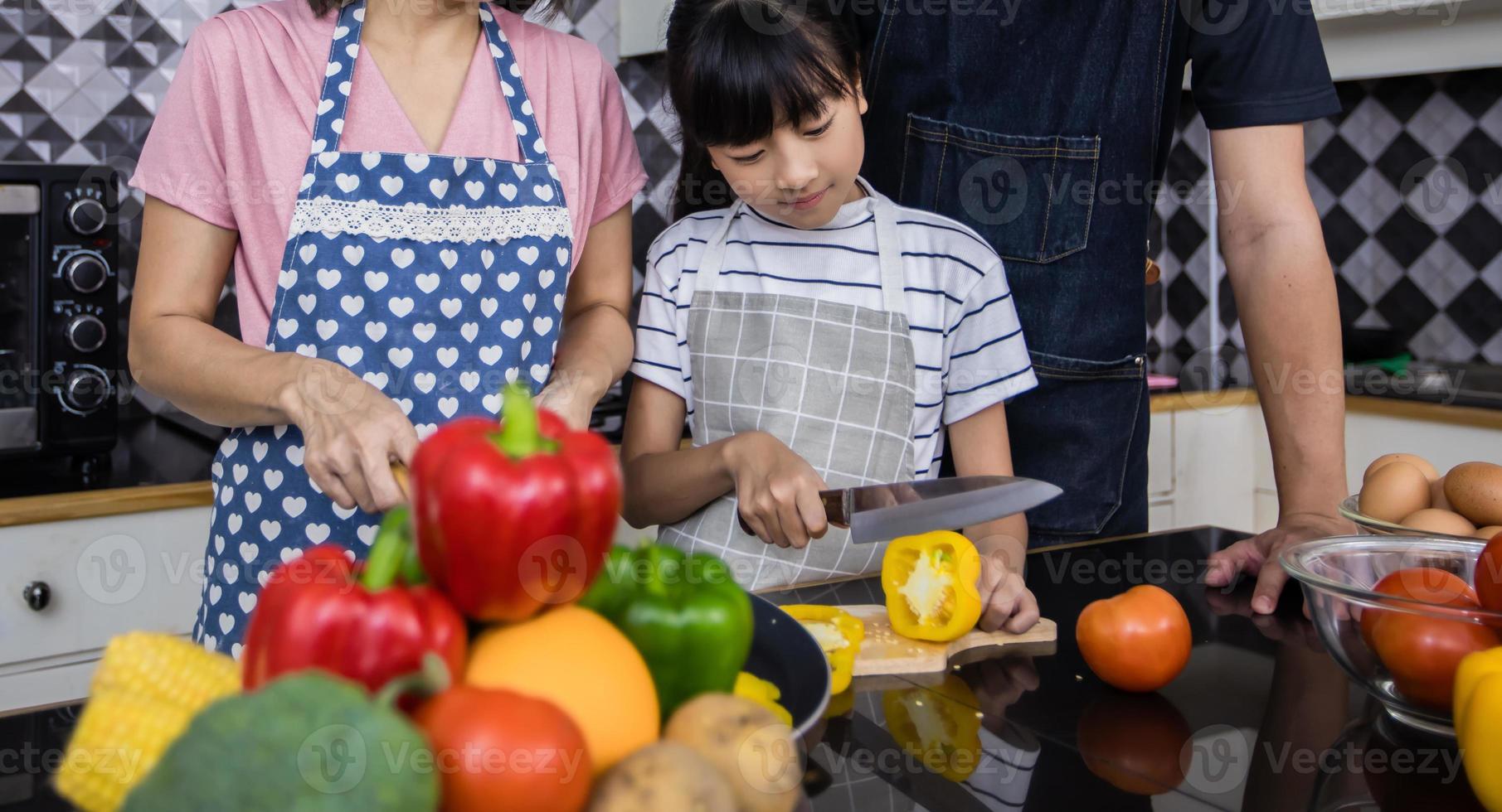 las familias asiáticas están cocinando y los padres están enseñando a sus hijas a cocinar en la cocina de casa. actividades familiares en vacaciones y felices en concepto de recreación foto