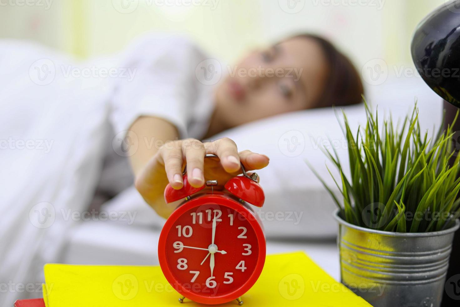 Asian woman happy waking up and turning off the alarm clock having a good day photo