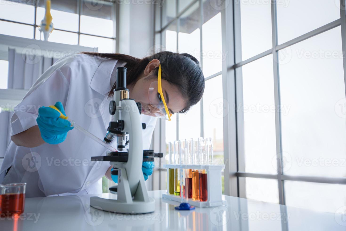 Medical Research and Scientists are working with a microscope and a tablet and Test Tubes, Micropipette and Analysis Results in a laboratory. photo