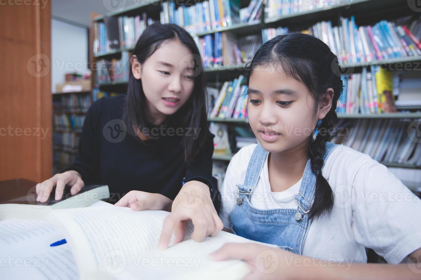 dos estudiantes asiáticas leyendo libros y usando un cuaderno en la biblioteca. foto