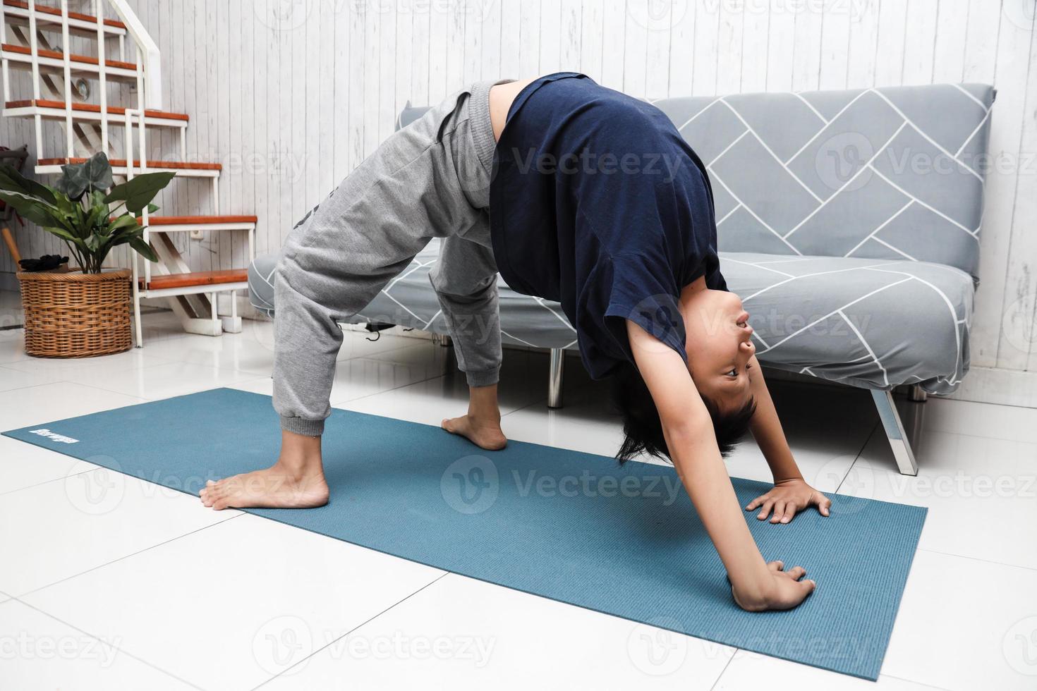 Asian boy on blue mat with yoga pose at home photo