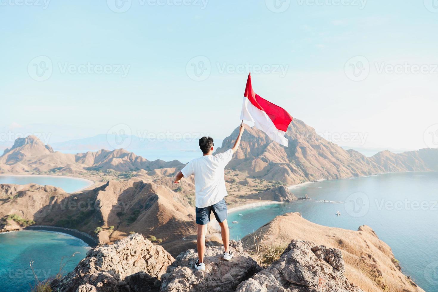 un hombre sosteniendo y ondeando la bandera indonesia en la cima de la montaña en labuan bajo indonesia foto