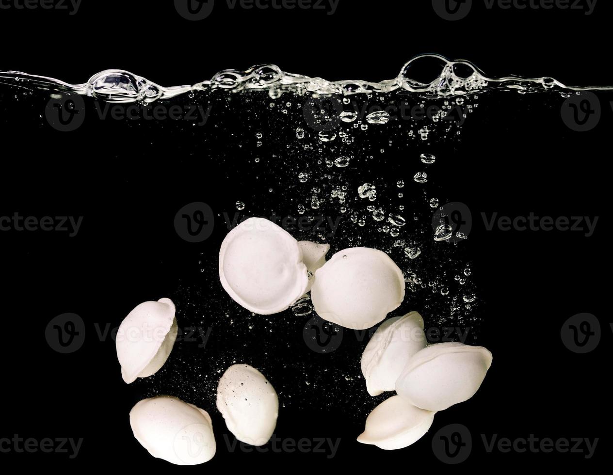 albóndigas bajo el agua en agua hirviendo bajo el agua en una sartén sobre fondo oscuro. comida, cocina italiana, china foto