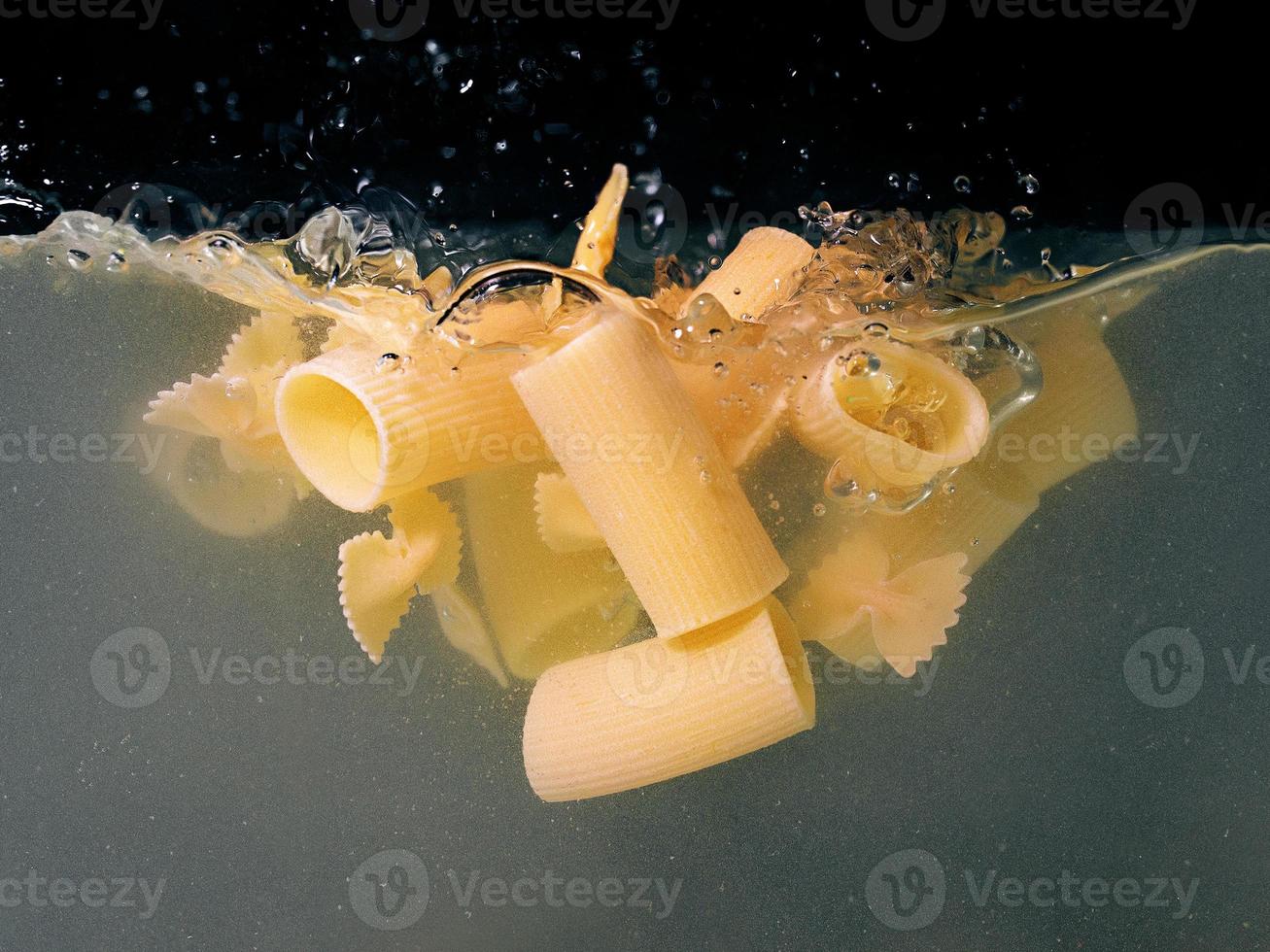 pasta falling in the boiling water on dark background. Underwater view. Cooking, cooking at home, italian cuisine concept photo