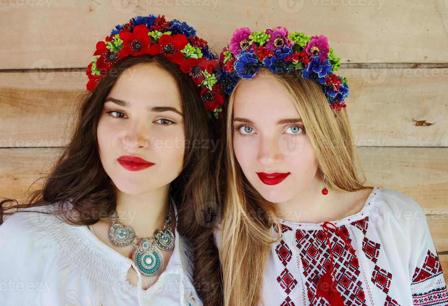 Two young beautiful women with long hair in Ukrainian blouses and in a wreathes in outdoor ethnic village in Kyiv Ukraine photo