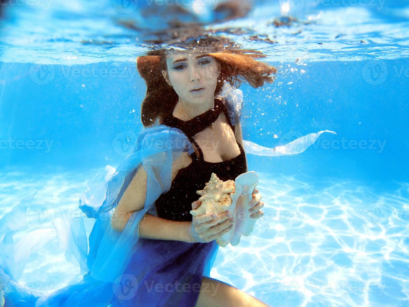 Underwater fashion portrait of beautiful young woman in blue dress photo