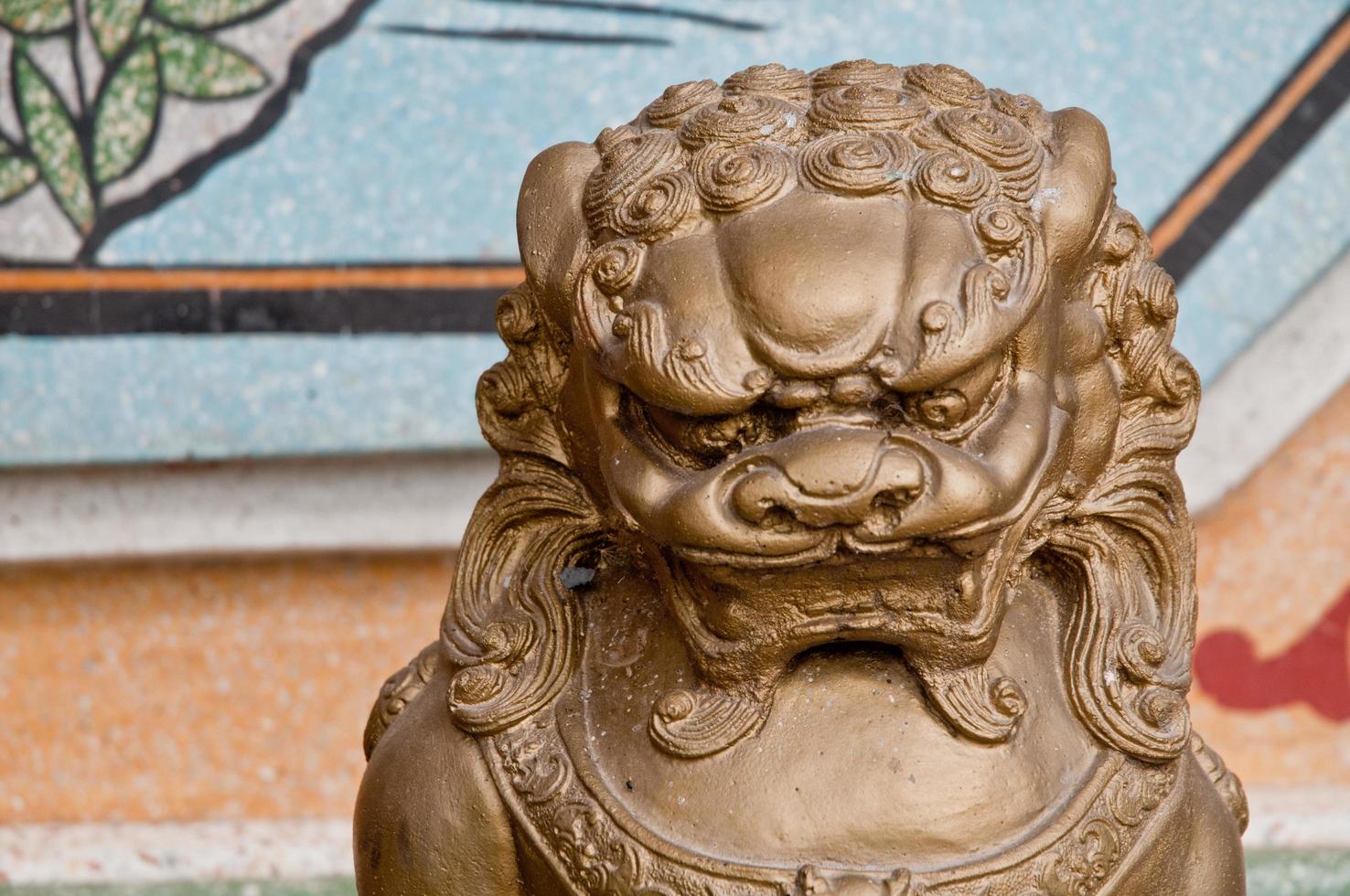 Strong and majestic golden dark bronze Asian Chinese lion metallic statue in a temple photo